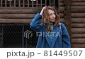 young red-haired woman in a blue coat and walks against the backdrop of the old city. portrait of a beautiful woman in the autumn city 81449507