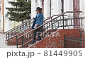 young red-haired woman in a blue coat and black hat with a suitcase on the background of the old city. traveler with map and suitcase 81449905