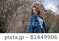 young red-haired woman in a blue coat and walks against the backdrop of the old city. portrait of a beautiful woman in the autumn city 81449906