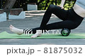 Girl on yoga mat massages the thigh muscles with an MFR roller. Myofascial release. 81875032