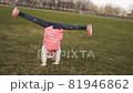 Active little girl doing cartwheel on green grass 81946862