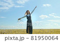 A young girl enjoys freedom. A girl is dancing in a field all alone with a bouquet of wild flowers. 81950064