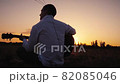 Alone man playing guitar outdoors at sunset time 82085046