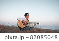 Alone man playing guitar sitting on the coast 82085048