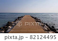 Wooden pier reinforced with stones. Calm sea and blue sky. Tourist season. 82124495
