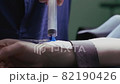 Patient inserts an intravenous catheter put into his arm in preparation for a surgery procedure. Reverse video 82190426