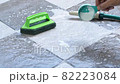 Pours detergent onto the wet tile floor to clean it. 82223084