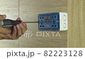 Electrician is using a screwdriver to install a power outlet on a wooden wall. 82223128