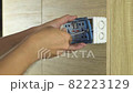 Electrician is using a screwdriver to install a power outlet on a wooden wall. 82223129
