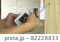 Electrician is using a screwdriver to tighten the wires to the electrical plug on a wooden wall. 82228833