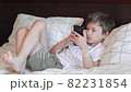 Boring boy laying on bed and playing on mobile phone 82231854