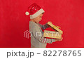Boy in a New Year's sweater on a red background. Child with a gift in hands in anticipation of Christmas. Young boy getting ready for the new year. Video of a child with a New Year's surprise 82278765