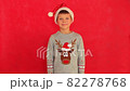 Boy in a New Year's cap and sweater on a red background. Child waiting for Christmas. Happy boy getting ready for the new year. 82278768