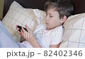 7 years old kid using gadget while laying in bed 82402346