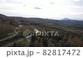 A mountain with a beautiful ridgeline that emerges beyond the primeval forest where the autumn leaves have advanced. 82817472