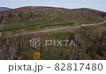 A mountain with a beautiful ridgeline that emerges beyond the primeval forest where the autumn leaves have advanced. 82817480