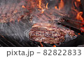 Searing and flipping ribeye steaks on grill 82822833