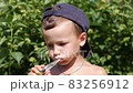 Little boy learns to brush his teeth correctly in summer garden 83256912