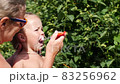 Little girl at age of two is brushing her teeth in summer garden 83256962
