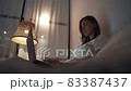Woman working at night in her bedroom using laptop computer lying on the bed 83387437