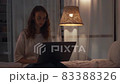 Young concentrated woman working at night in her bedroom using laptop computer and typing message 83388326