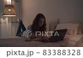 Woman working at night in her bedroom using laptop computer lying on the bed 83388328