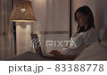 Woman working at night in her bedroom using laptop computer lying on the bed 83388778