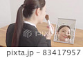 鏡を見ながらメイクをするスーツ姿の若い女性 83417957