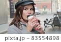Young beautiful girl drinking coffee on the street. The girl enjoys morning coffee before work 83554898