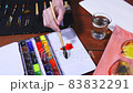 The artist mixes watercolor paints in a palette with a brush. 83832291