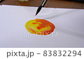 The artist paints an abstract figure on a white canvas with watercolor paints. 83832294