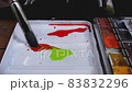 The artist mixes watercolor paints in a palette with a brush. 83832296
