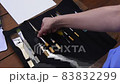The woman unfolds a rag pencil case and takes out a brush for drawing. 83832299
