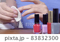 A woman using a cotton pad erases a layer of nail polish from her nails. Close-up shot. Nail care, cosmetic procedure 83832300