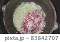 Cooking in a cauldron in the open air on a fire. food from onions and chicken meat is prepared in a cast iron cauldron. Preparation pilaf 83842707