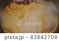Rice in a cauldron in the process of cooking pilaf on a traditional Asian oven. 83842708