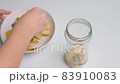 A person making banana peel fertilizer with banana cuts. Putting small pieces of banana skin into the glass jar and pouring water 83910083