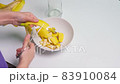 A person making banana peel fertilizer with banana cuts. A woman hand cutting banana skin into small pieces 83910084