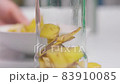 A person making banana peel fertilizer with banana cuts. Putting small pieces of banana skin into the glass jar and pouring water 83910085