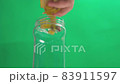 A person making banana peel fertilizer with banana cuts. Putting small pieces of banana skin into the glass jar and pouring water 83911597
