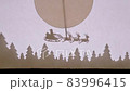 Puppet Shadow Theatre. Santa Claus on a sleigh with reindeer flies over the forest under the big moon 83996415