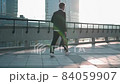 Young manager go over the bridge in the city against the background of the sunrise and drinks coffee. Slow mo, back view 84059907
