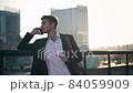 Young businessman talking on the phone on the bridge against the background of unfinished buildings. Early morning. 84059909