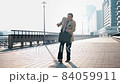 An aged businessman is dancing on the street and is happy. Sunny morning. 84059911