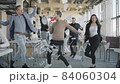 Incredible fun in the office. Employees dance, scatter money and paper, a colleague shouts in a trumpet . The atmosphere of celebration and victory. Creative office space. 84060304