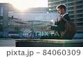 Young stylish businessman outdoors walks to the bench sits down uses a smartphone and leaves. 84060309