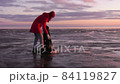A woman cleans the bank of plastic bottles and puts the trash in a garbage bag. Environmental pollution by plastic. Recyclable packaging. 84119827