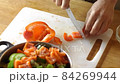 Close up cook cuts sweet pepper on a cutting board. 84269944