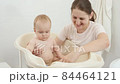 Cheerful smiling baby with mother playing while washing in bath. Concept of children hygiene, healthcare and parenting. 84464121