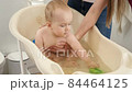 Cheerful smiling baby boy playing toys and splashing water in plastic children bath. Concept of children hygiene, healthcare and parenting. 84464125